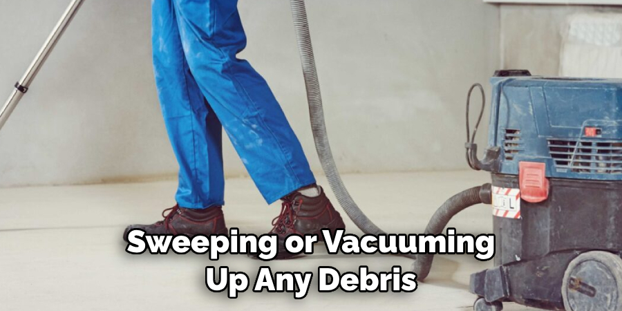 Sweeping or Vacuuming Up Any Debris